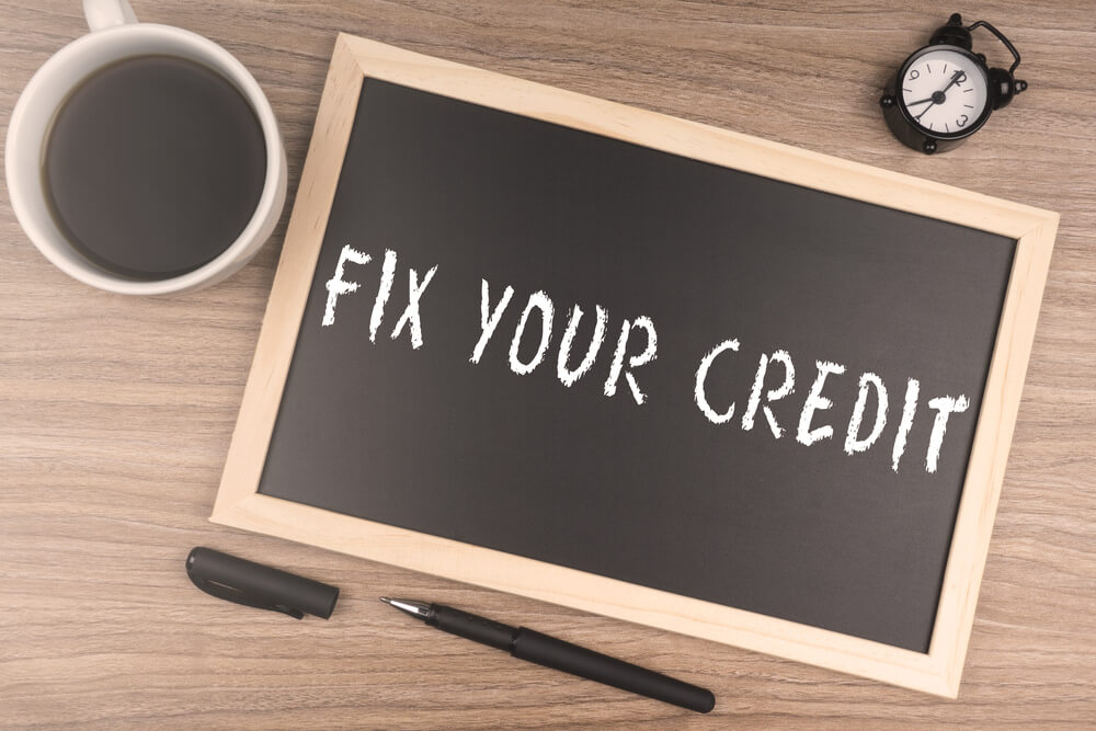 Fix Your Credit Written on a School Board, Left on a Table Next to a Clock and a Cup of Coffee