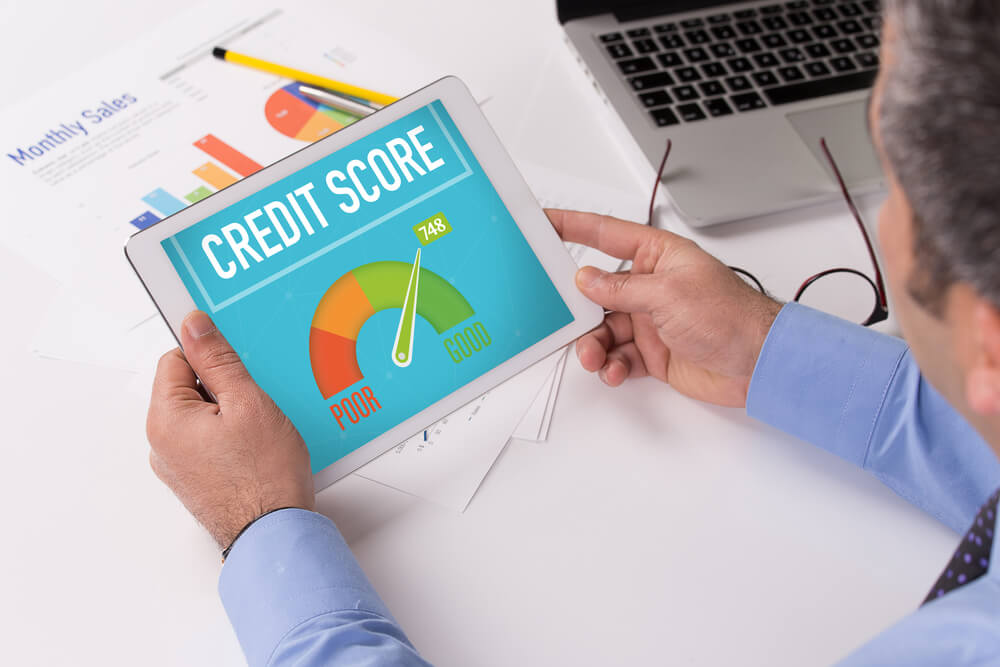 Man Working On Tablet With Credit Score on a Screen